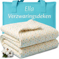 Ella verzwaringsdeken met stippenprint in crème, gevouwen naast een turquoise draagtas.