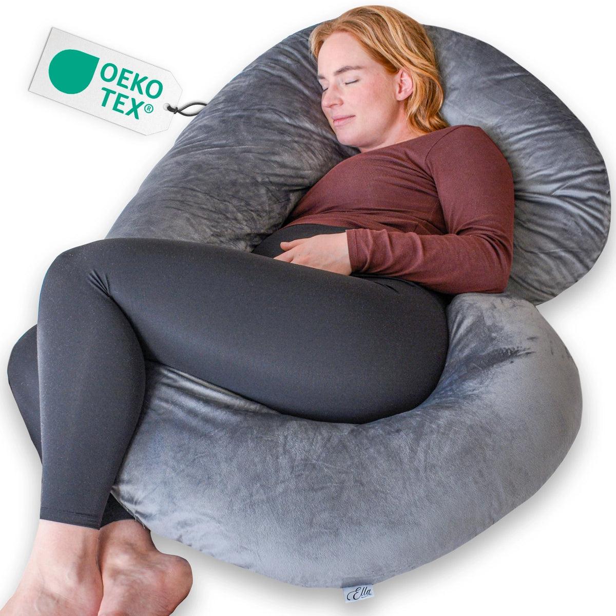 Vrouw ligt op een groot grijs kussen van Ella Sleeps C - Shape Minky, ideaal voor comfort tijdens de zwangerschap.