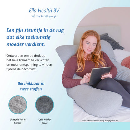 Vrouw op bed met een tablet, comfortabel leunend tegen een zwangerschapskussen van Ella Sleeps.
