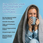 Frau sitzt in die Sherpa-Therapiedecke gehüllt und hält eine Tasse, daneben eine Liste mit sechs Punkten von „das beruhigende Gefühl einer Umarmung“ bis „mentale Klarheit & Konzentration fördern“