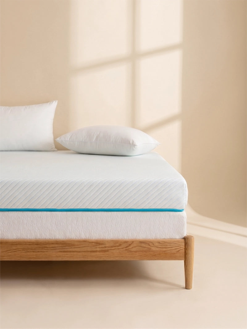 Ella matrastopper van 10 cm op een opgemaakt bed met kussen.